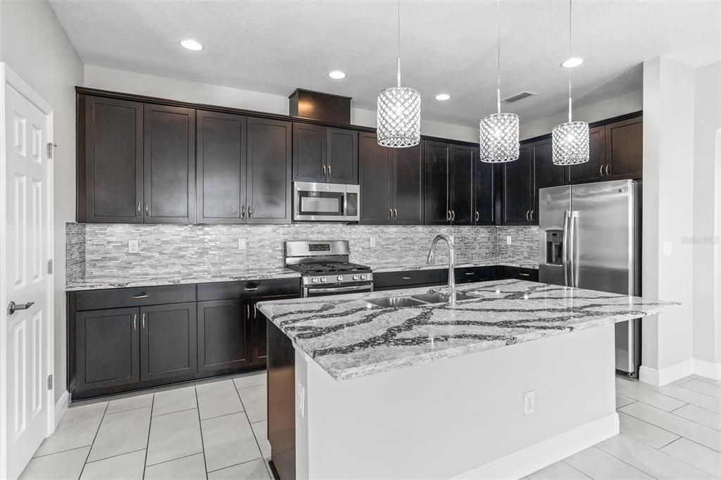 6906 Paradiso Drive Apollo Beach, FL 33572 - Photo 7 of 37 a kitchen with kitchen island granite countertop a sink a center island a stove and a cabinets