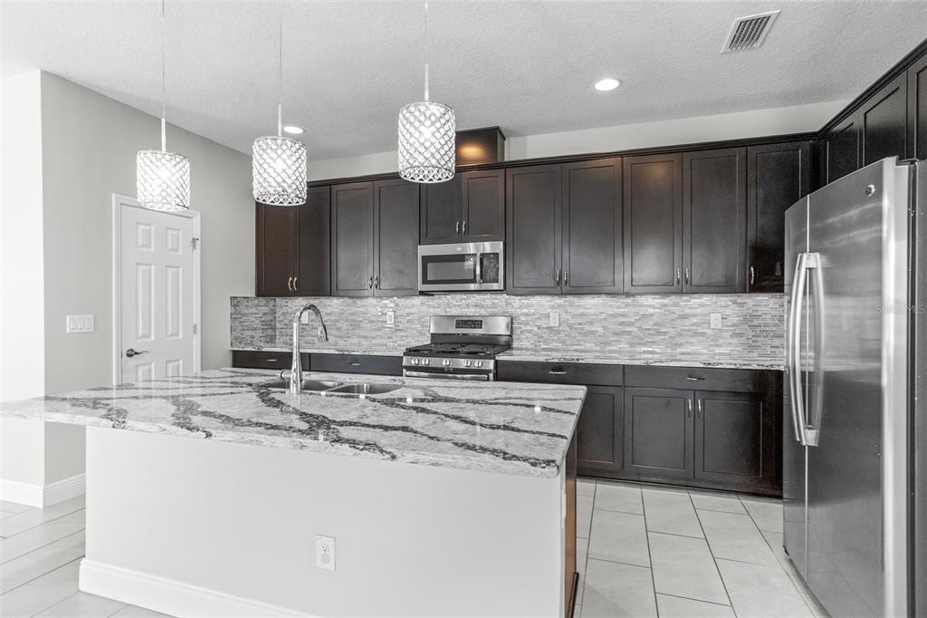 6906 Paradiso Drive Apollo Beach, FL 33572 - Photo 8 of 37 a kitchen with stainless steel appliances granite countertop a sink and a stove