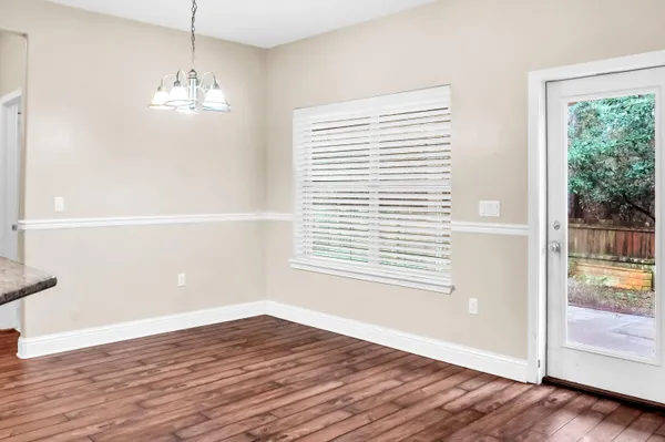 a view of an empty room with window and chandelier fan