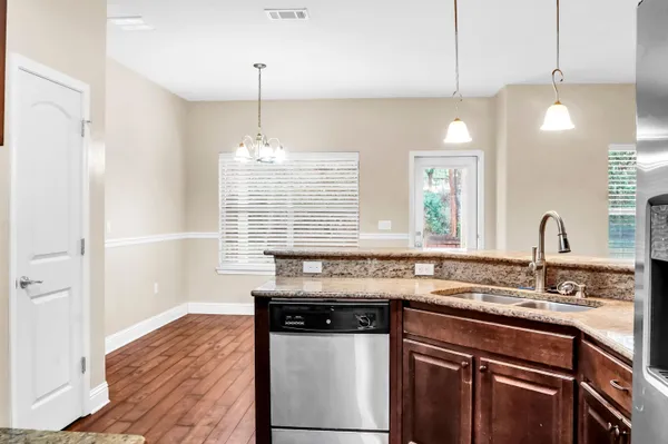 a kitchen with granite countertop a sink cabinets and stainless steel appliances