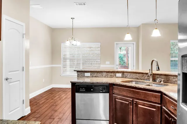 a kitchen with granite countertop a sink cabinets and stainless steel appliances
