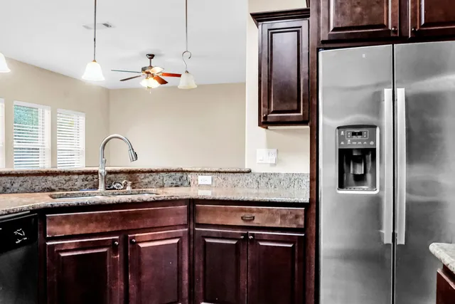 a kitchen with stainless steel appliances granite countertop a refrigerator a stove and a sink with wooden cabinets