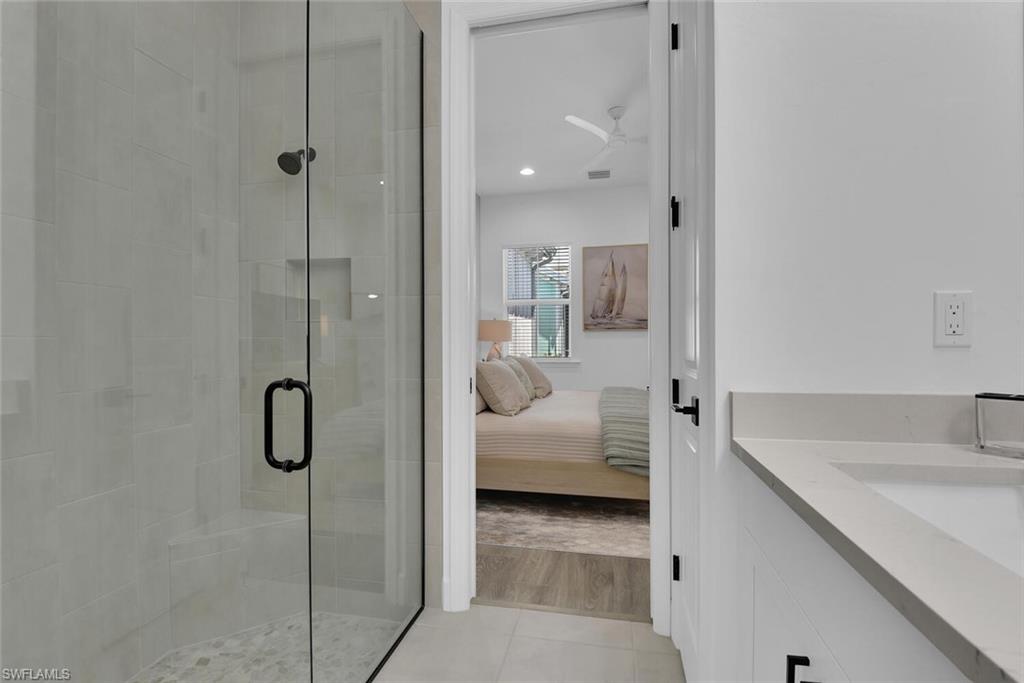 7242 Saona Court Naples, FL 34113 - Photo 15 of 34 a en suite bathroom with a granite countertop sink and shower