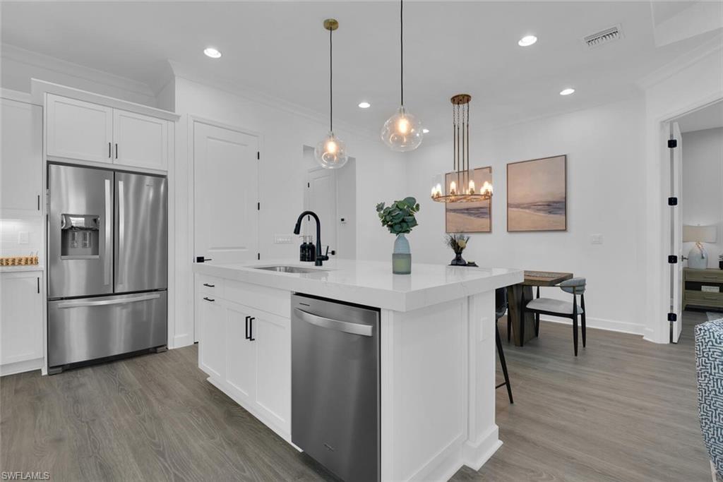 7242 Saona Court Naples, FL 34113 - Photo 5 of 34 a kitchen with stainless steel appliances a refrigerator a sink a stove a microwave and wooden floor