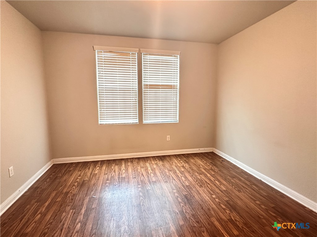 264 Trestle Tree, Unit A San Marcos, TX 78666 - Photo 9 of 17 an empty room with wooden floor and windows