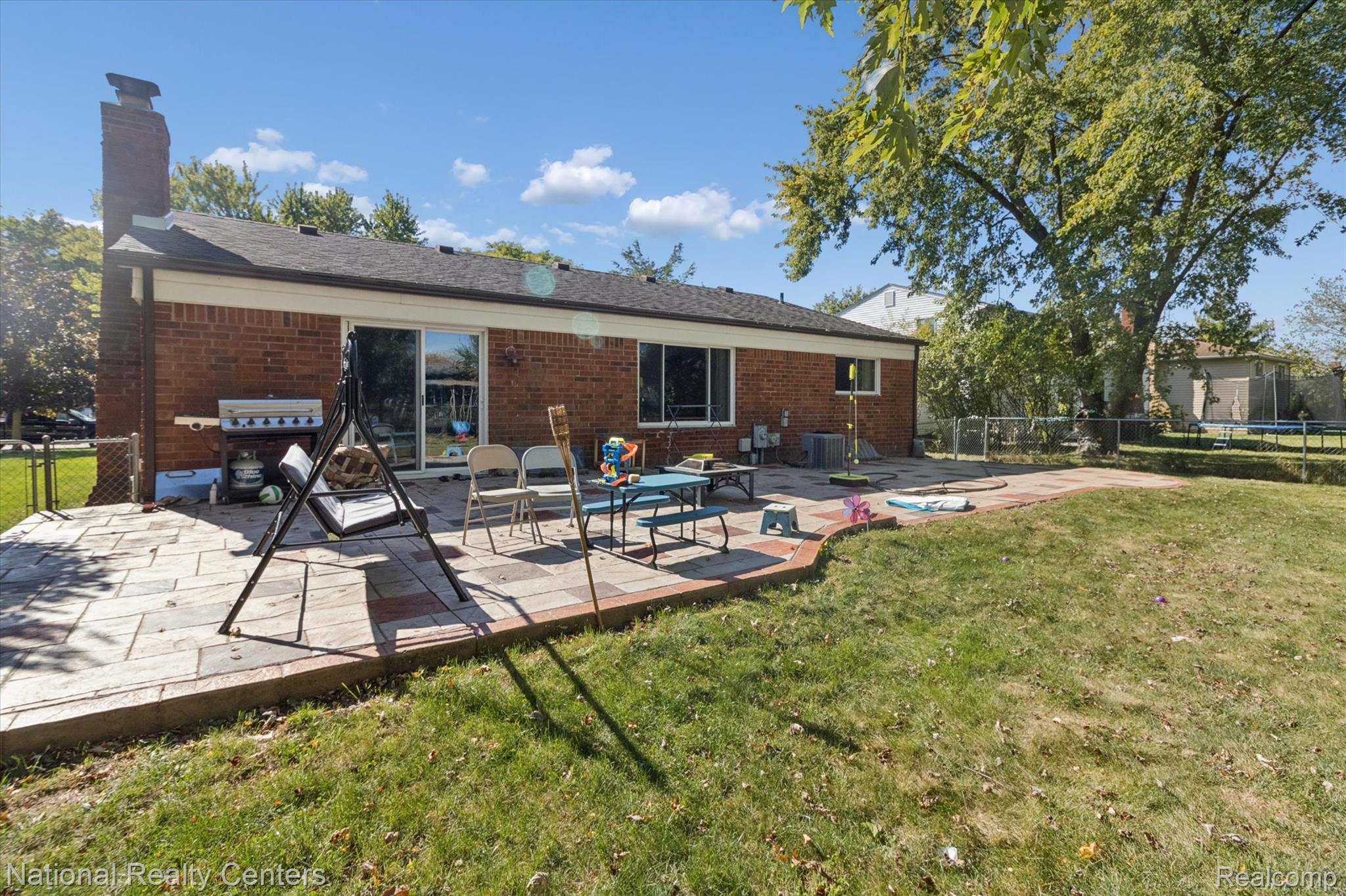 44768 Hanford Road Canton, MI 48187 - Photo 32 of 36 Back of house with a patio area, a trampoline, a chimney, and brick siding