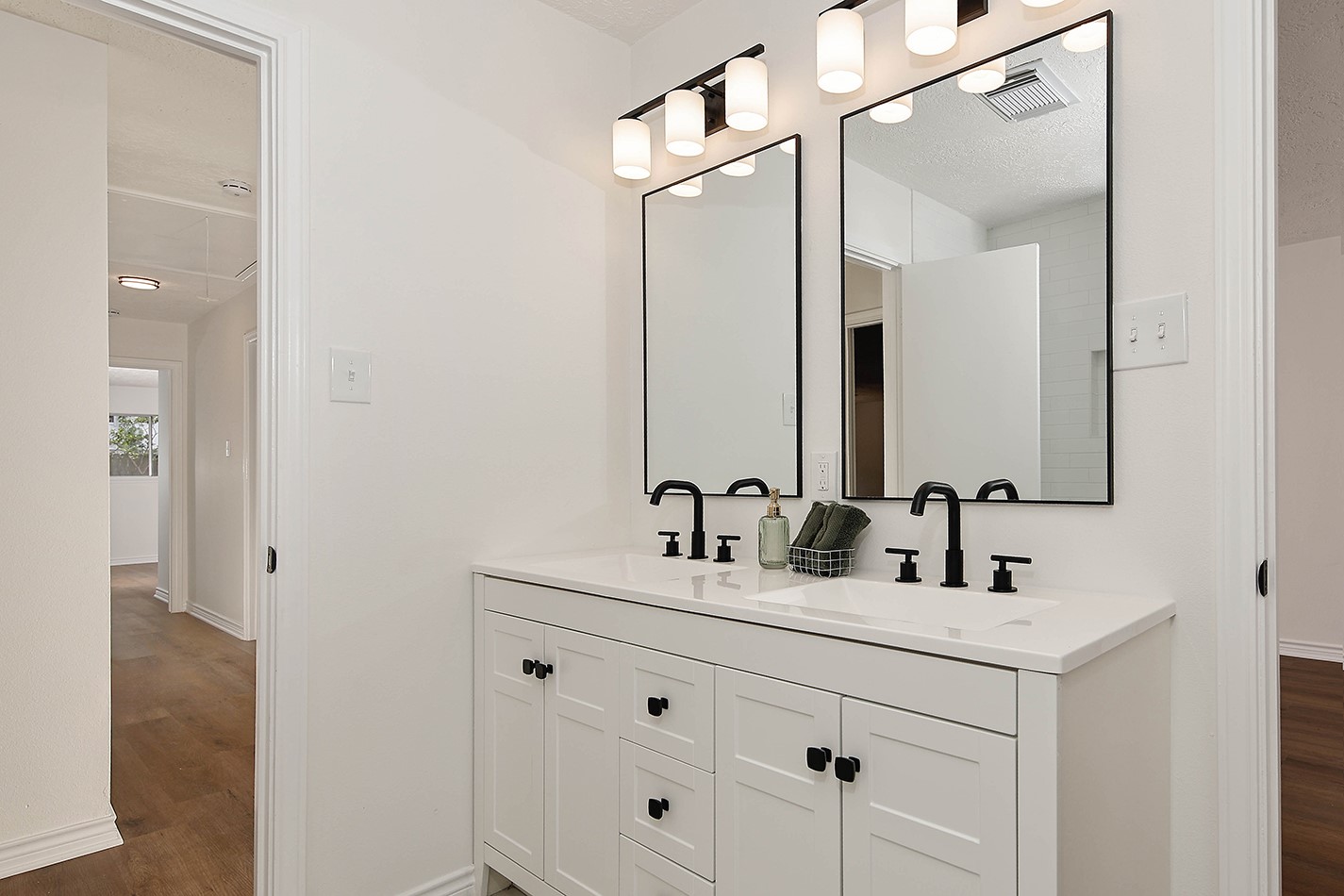 19410 Craigchester Lane Spring, TX 77388 - Photo 21 of 32 Bathroom 2 has a modern custom vanity in crisp white with sharp black accents and has dual sinks with quartz counters. New black plumbing fixtures, lighting, mirrors, cabinet pulls and hardware.