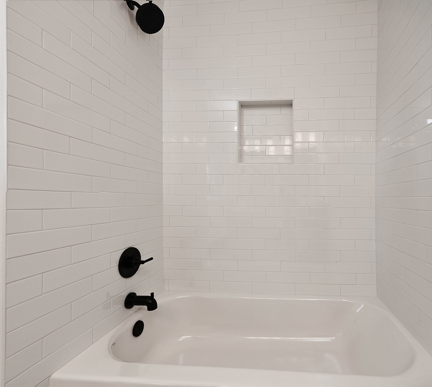 19410 Craigchester Lane Spring, TX 77388 - Photo 22 of 32 Bathroom 2 has new tub and shower with light and bright tile including recessed niche for bottle storage and fabulous black fixtures.