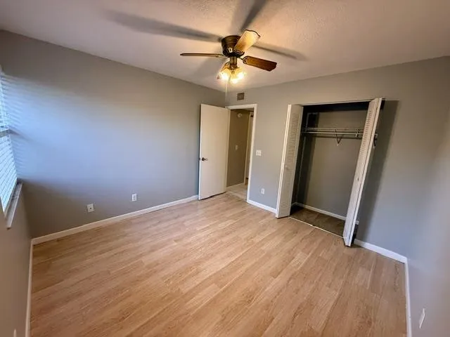 an empty room with closet and a ceiling fan