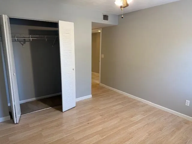an empty room with wooden floor closet and windows