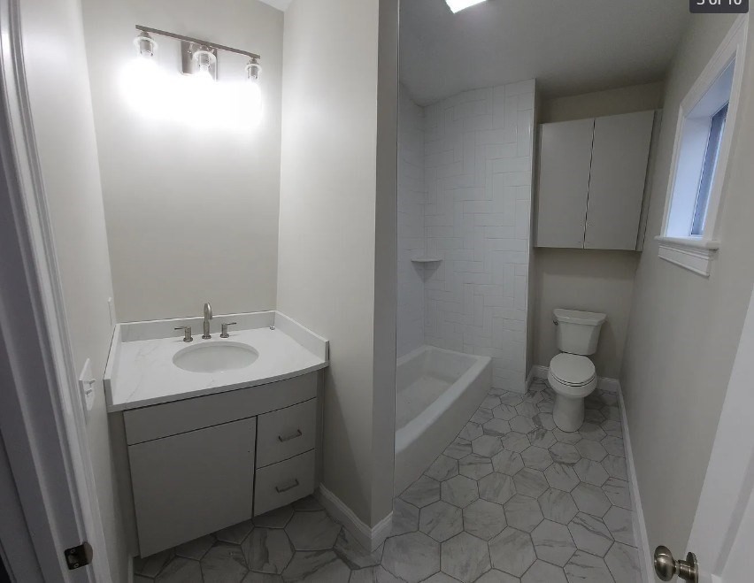 322 Brownell Street, Unit 1E Fall River, MA 02720 - Photo 2 of 6 a spacious bathroom with a toilet sink and mirror