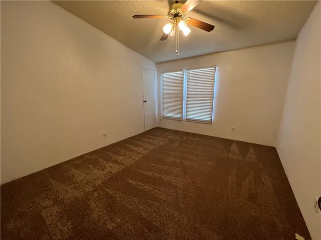 an empty room with a chandelier fan and windows