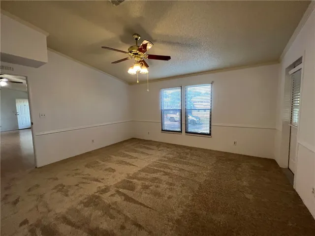 an empty room with windows and fan