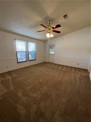 an empty room with windows and fan