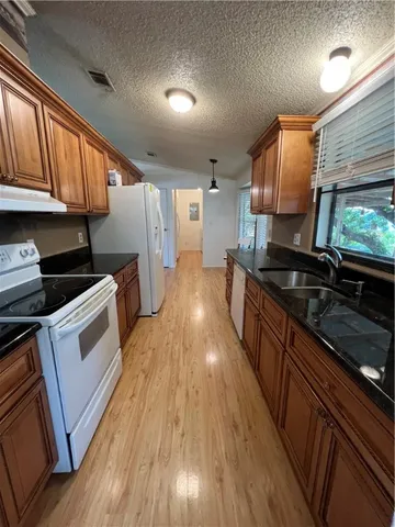 a kitchen with granite countertop wooden floors stainless steel appliances and a window