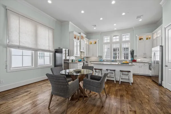 a dining room with stainless steel appliances a dining table wooden floor and a large window