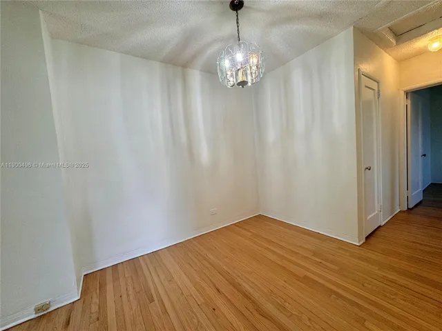 a view of a hallway with wooden floor and chandelier