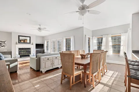 a dining room with furniture a fireplace a rug a flat screen tv and couches