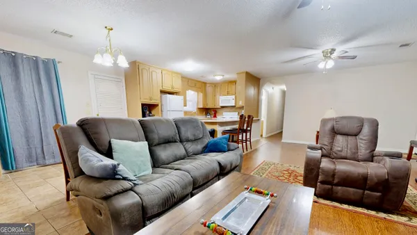 a living room with furniture kitchen view and a chandelier