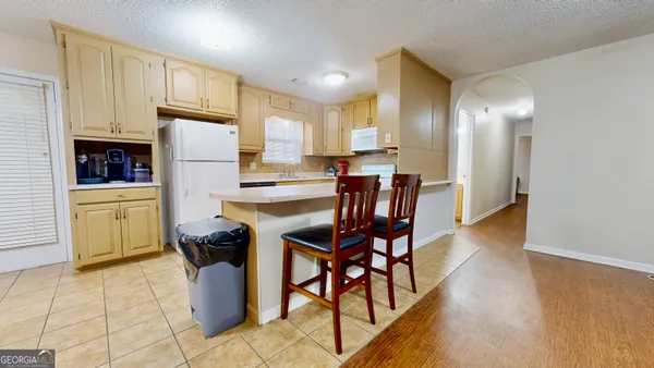 a kitchen with stainless steel appliances a refrigerator a stove a sink cabinets and a dining table