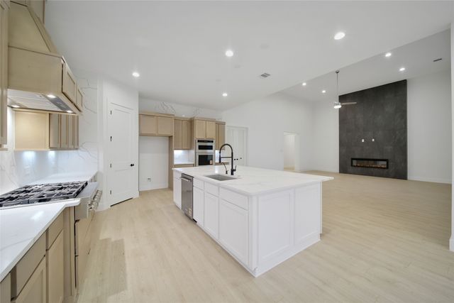 a large white kitchen with stainless steel appliances sink a stove and a refrigerator