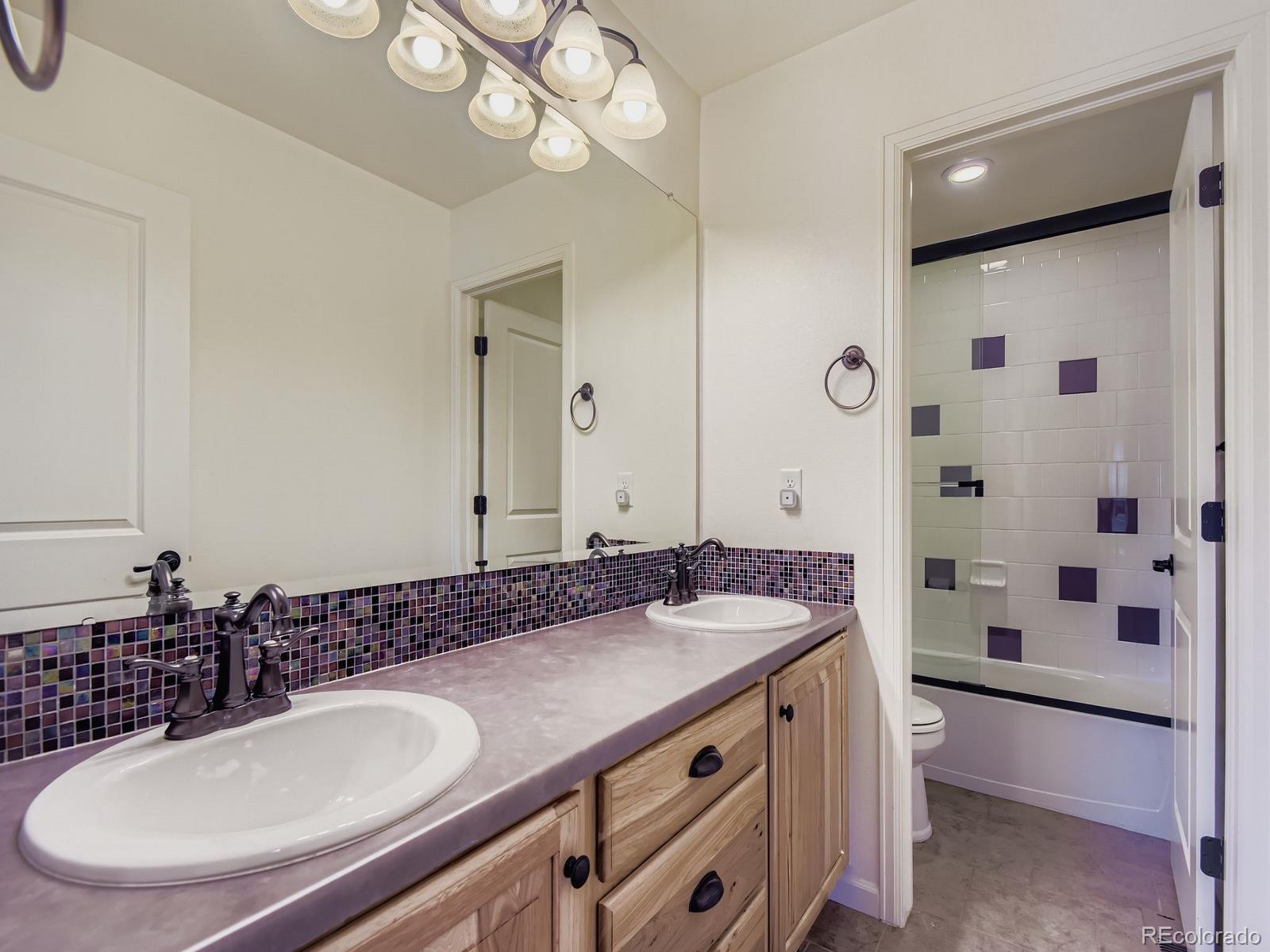 3839 Donnington Circle Castle Rock, CO 80104 - Photo 21 of 31 a bathroom with a granite countertop sink a mirror and a shower