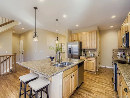a kitchen with stainless steel appliances granite countertop sink stove refrigerator dining table and chairs