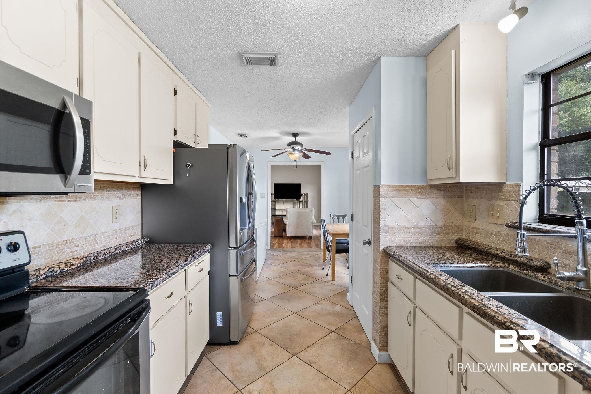 33135 Collier Road Lillian, AL 36549 - Photo 13 of 30 Kitchen featuring stainless steel appliances, backsplash, a textured ceiling, light tile patterned floors, and dark stone counters