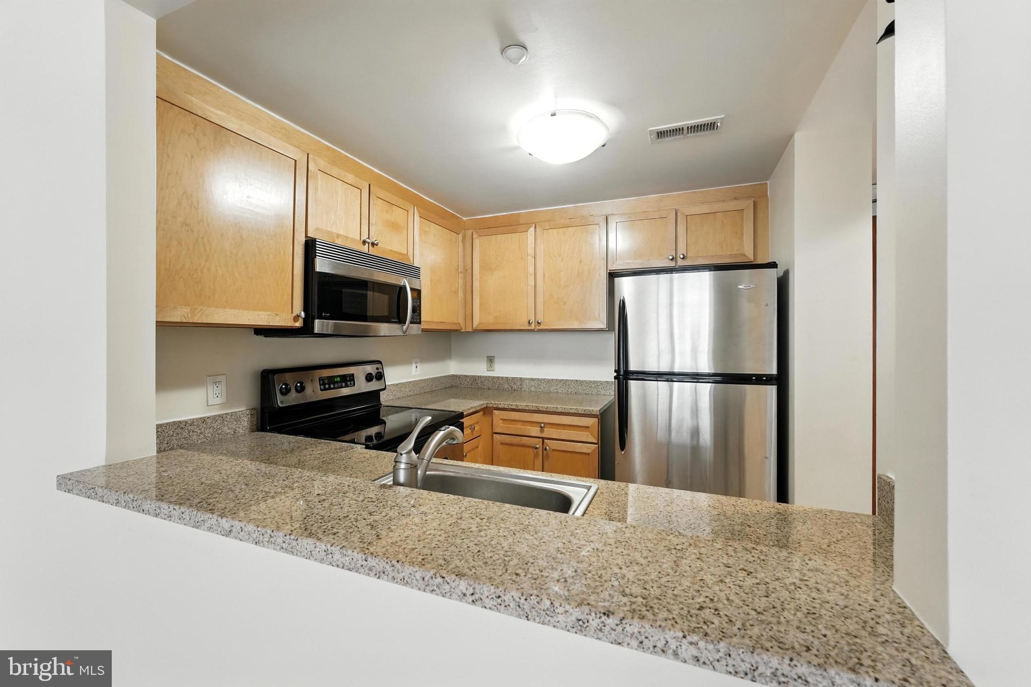 1150 K Street Northwest, Unit 1207 Washington, DC 20005 - Photo 20 of 29 a kitchen with granite countertop a refrigerator and a sink