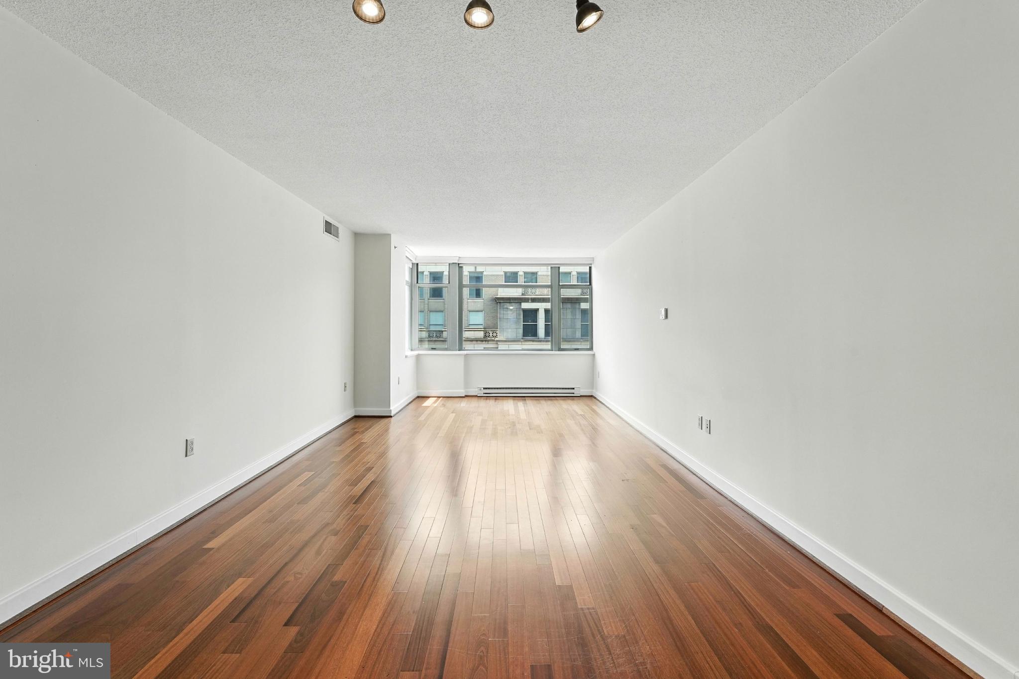 1150 K Street Northwest, Unit 1207 Washington, DC 20005 - Photo 21 of 29 an empty room with wooden floor and windows