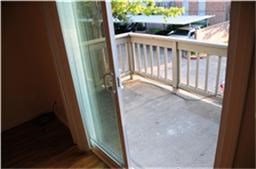6001 Reims Road, Unit 1202 Houston, TX 77036 - Photo 12 of 16 This photo shows a small balcony accessible through a sliding glass door, offering outdoor space with a railing and a view of a tree and adjacent buildings.