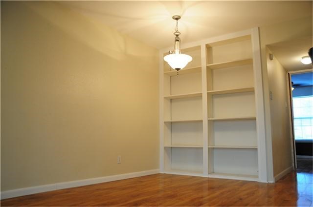 6001 Reims Road, Unit 1202 Houston, TX 77036 - Photo 13 of 16 This room features hardwood floors, a built-in bookshelf, and a chandelier, offering a cozy and functional space.