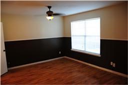 6001 Reims Road, Unit 1202 Houston, TX 77036 - Photo 3 of 16 This room features hardwood flooring, a ceiling fan, and a large window. The walls are two-toned with a darker shade on the lower half, creating a stylish contrast.
