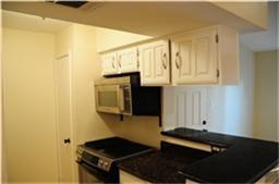 6001 Reims Road, Unit 1202 Houston, TX 77036 - Photo 7 of 16 Cozy kitchen with white cabinets, black countertops, and a built-in microwave. Compact layout ideal for efficiency.