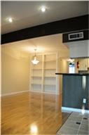 6001 Reims Road, Unit 1202 Houston, TX 77036 - Photo 9 of 16 This photo showcases a bright, open living area with polished wood flooring, built-in shelving, and recessed lighting. There's a partial view of a kitchen bar area, adding a modern touch.