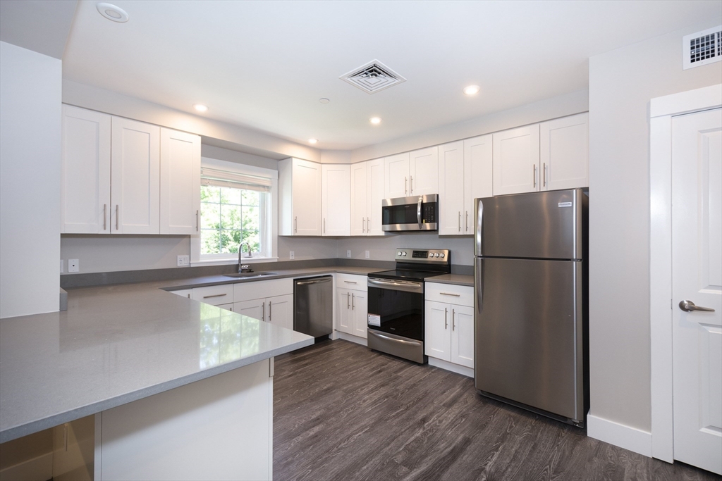 50 Country Way, Unit C204 Scituate, MA 02066 - Photo 2 of 22 a kitchen with a refrigerator a sink and wooden cabinets