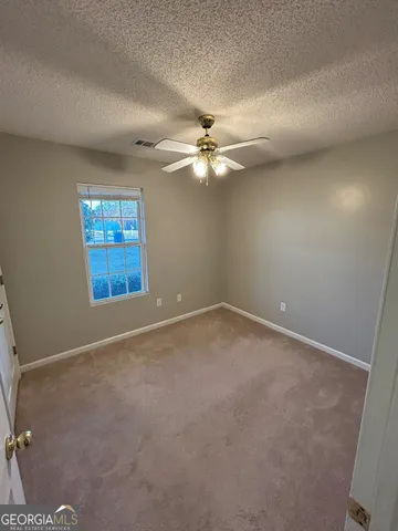 an empty room with windows and ceiling fan