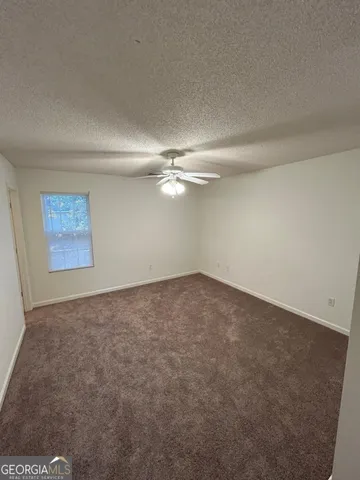 an empty room with a ceiling fan and window
