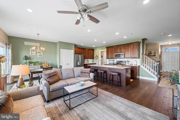 a living room with furniture kitchen view and a wooden floor