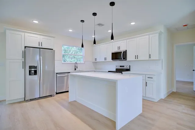 a kitchen with kitchen island white cabinets and sink