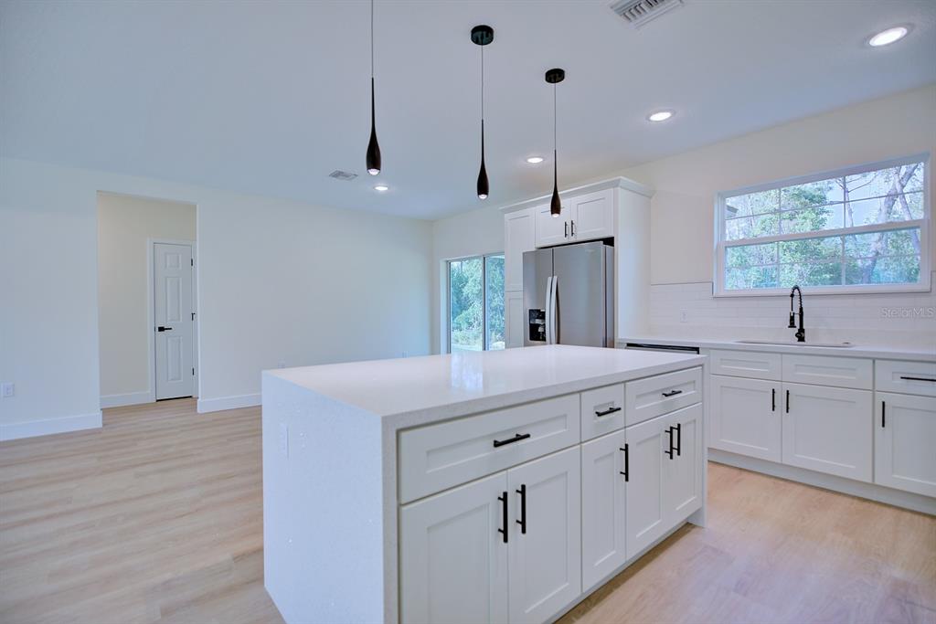 8724 Capilla Street Sebring, FL 33872 - Photo 10 of 33 a kitchen with kitchen island white cabinets and sink