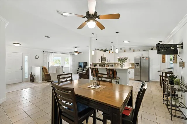a dining room with stainless steel appliances kitchen island granite countertop a dining table chairs and a refrigerator