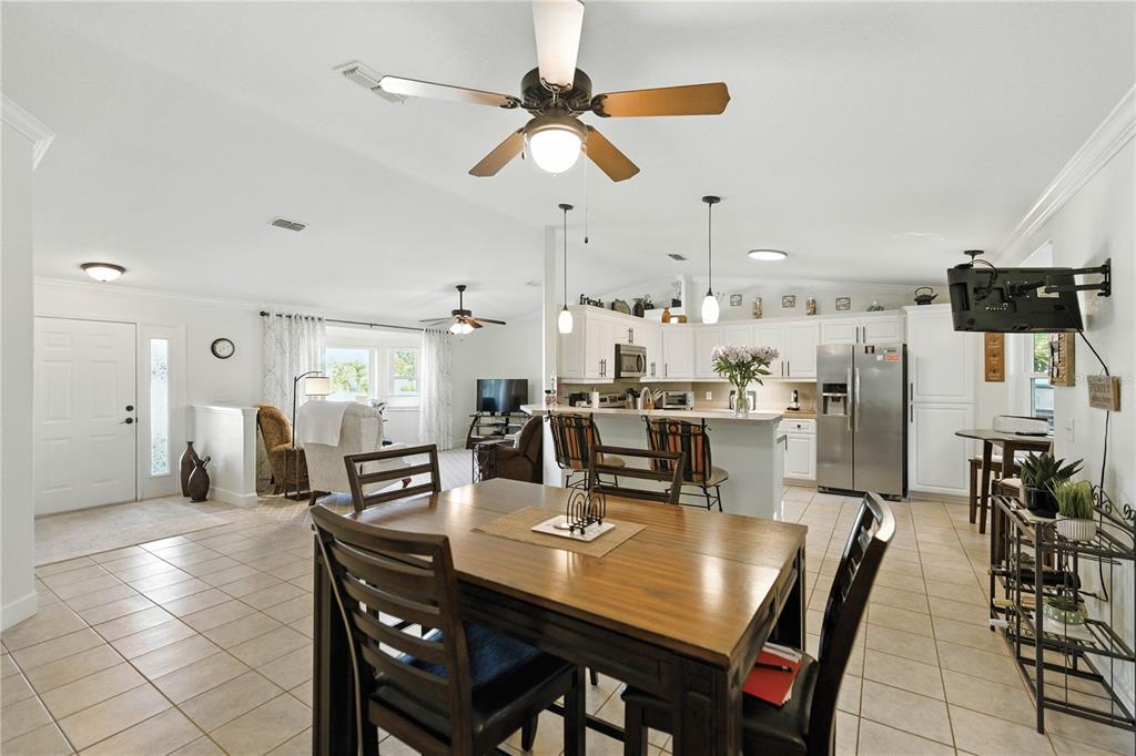 5968 Southwest 103rd Loop Ocala, FL 34476 - Photo 4 of 48 a dining room with stainless steel appliances kitchen island granite countertop a dining table chairs and a refrigerator