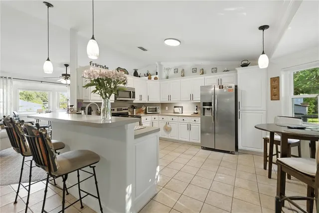 a kitchen with stainless steel appliances granite countertop a refrigerator a sink a stove a dining table and chairs