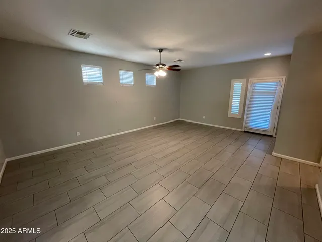 an empty room with windows and ceiling fan