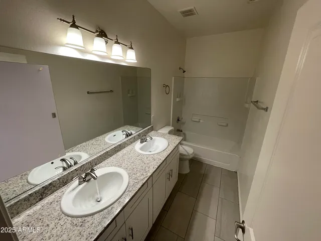 a bathroom with a granite countertop double vanity and a mirror