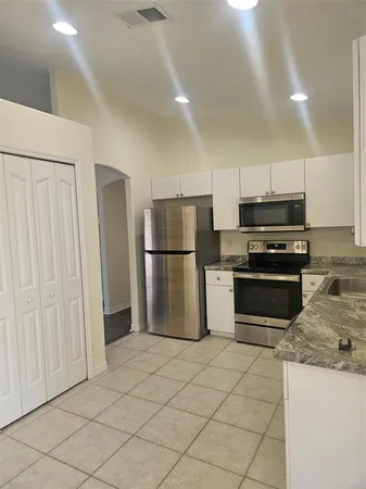 a kitchen with granite countertop a refrigerator and a stove top oven