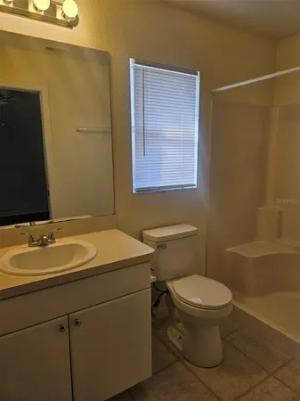 a bathroom with a granite countertop sink toilet and a mirror