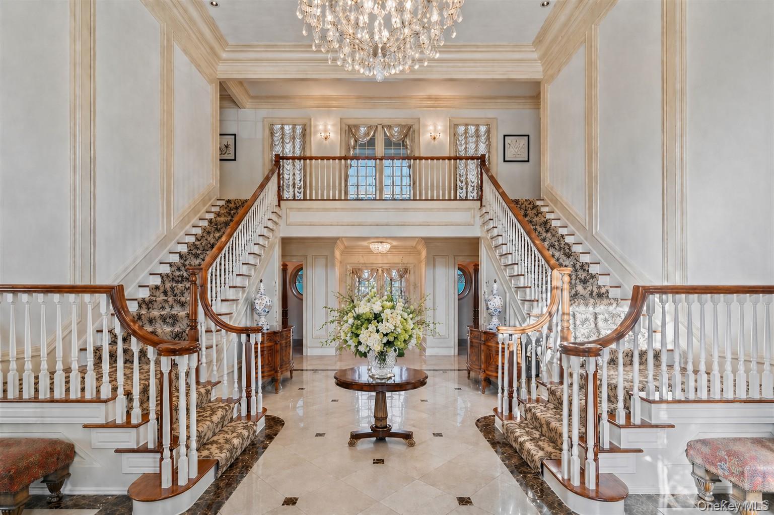 660 Chicken Valley Road Locust Valley, NY 11560 - Photo 3 of 48 Grand foyer featuring a dual curved staircase with patterned carpet runners, hardwood handrails, and white balusters