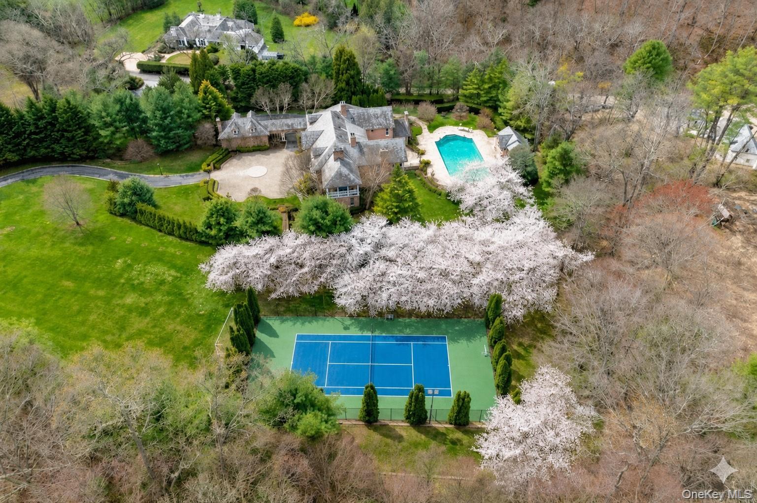 660 Chicken Valley Road Locust Valley, NY 11560 - Photo 47 of 48 Aerial perspective showcasing a comprehensive property layout with a tennis court, swimming pool, extensive green lawns, mature trees, and a stone-clad residence